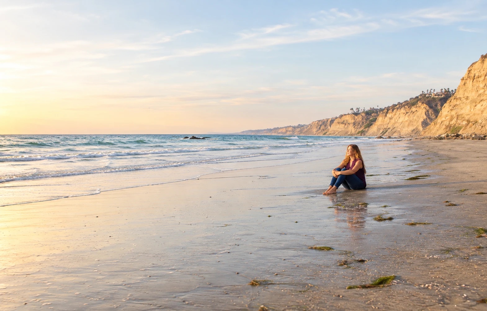 Sienna sitting on the beach at sunset below the bluffs