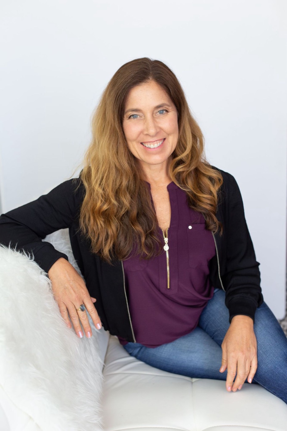 Sienna Smith smiling, seated on a white chair in a bright room